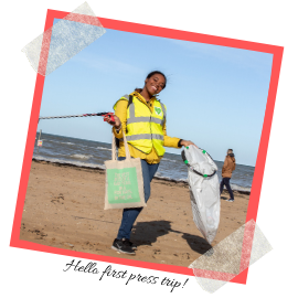 Photo of me picking up litter on the beach. Caption reads: Hello first press trip!