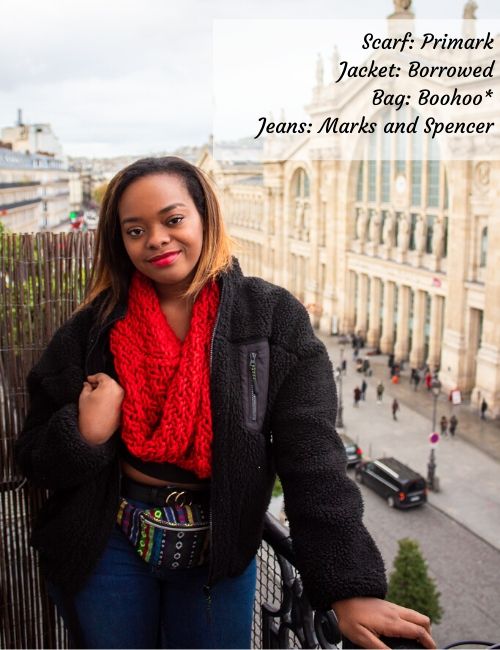 Picture of me on a balcony in a red scarf, fluffy black coat and bumbag.