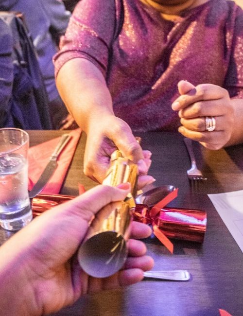 A photo of two people pulling a gold cracker