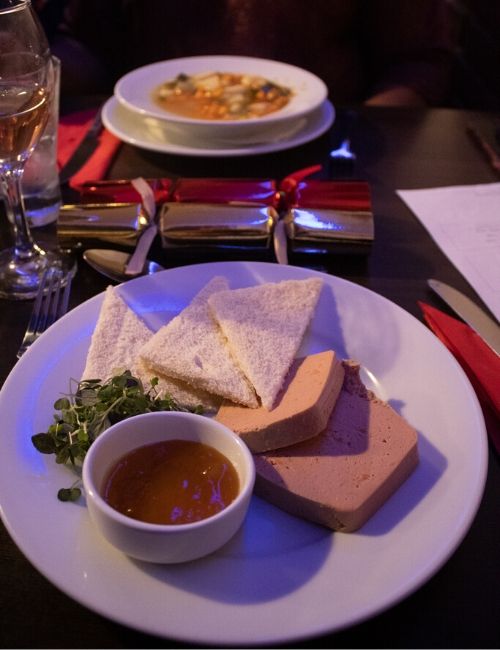 A photo of two slices of pate, some melba toast and some chutney.