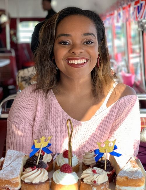 photo of author smiling whilst sitting on bus with afternoon tea in front of her