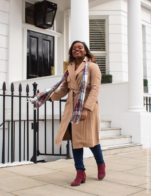 :hoto of me in a long, beige trench coat, jeans, and a scarf, walking down the road. The coat is from the Frankie x Oasis collaboration.