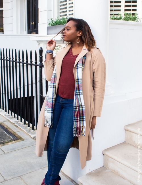 :hoto of me in a long, beige trench coat, jeans, and a scarf, walking down the road. The coat is from the Frankie x Oasis collaboration.