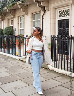 Photo of author in white jacket, white top and jeans, the perfect transitional clothing for autumn. She is looking off to the side