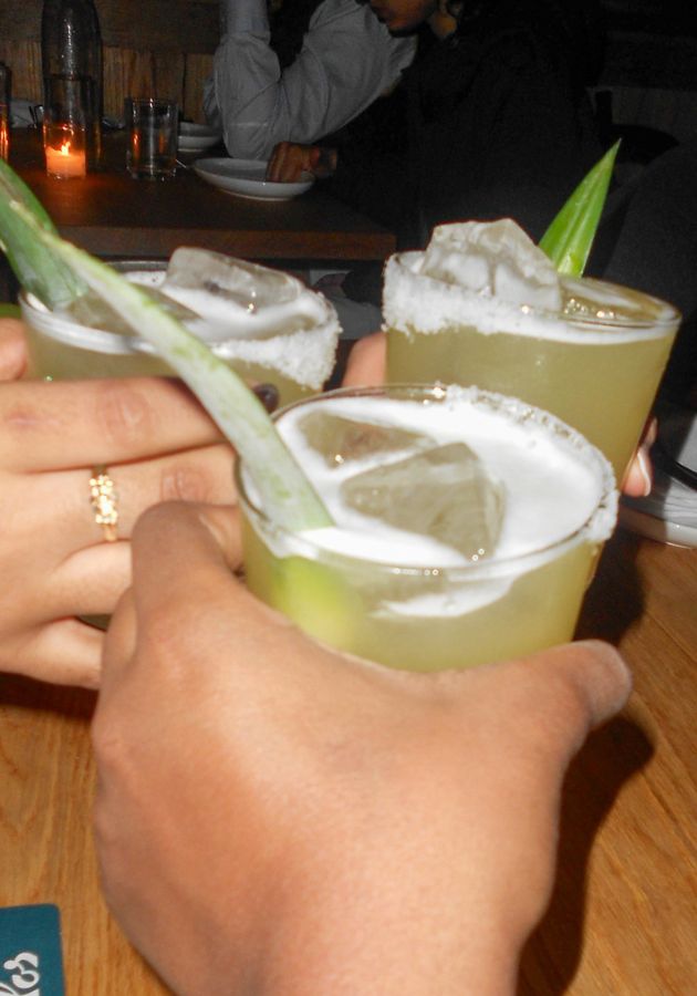 A photo of 3 friends cheersing spicy pineapple margaritas